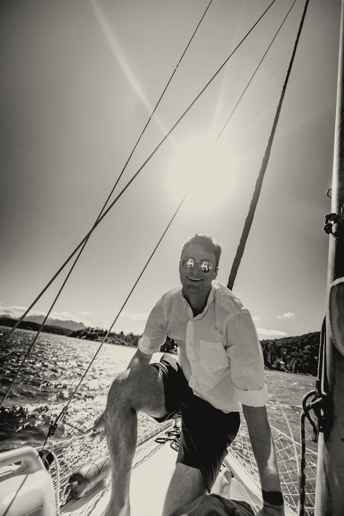 Man in white on the deck of a large sailboat in the sun