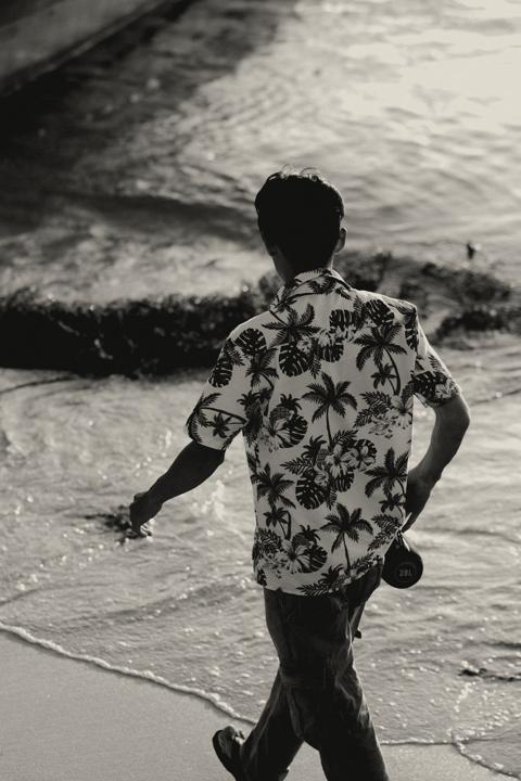 Man in a print camp shirt walking along the shoreline